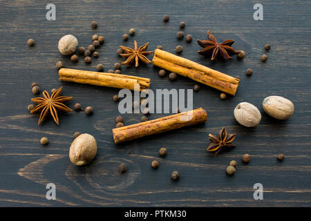 Le spezie intere al buio su un sfondo di legno Foto Stock