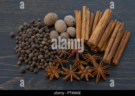Le spezie intere al buio su un sfondo di legno Foto Stock