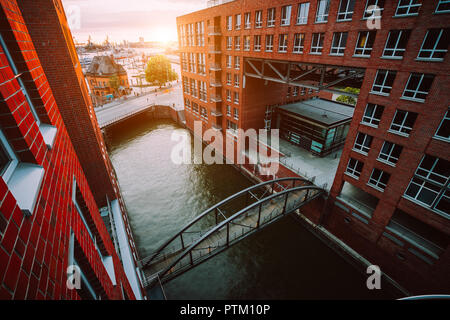 HafenCity. Ponte sul canal e palazzi in mattoni rossi nel vecchio distretto warehouse Speicherstadt di Amburgo in golden ora la luce del tramonto, Germania. Vista da sopra Foto Stock