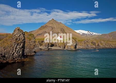 Casa sulla costa di basalto off Stapafell mountain e Snaefellsjoekull ghiacciaio, Arnarstapi, Snaefellsnes, Vesturland, Islanda Foto Stock