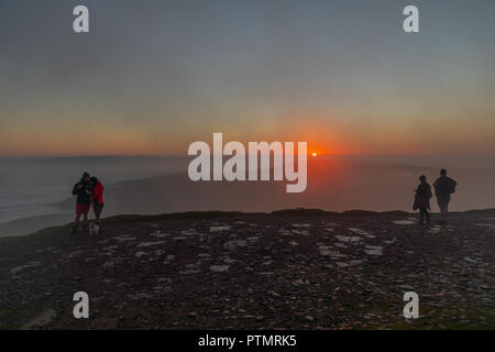 Pen y ventola, Brecon Beacons, Wales, Regno Unito. Il 10 ottobre 2018. Hill walkers godono di una drammatica sunrise dal picco del Pen y Fan, la montagna più alta nel sud della Gran Bretagna si trova in Brecon Beacons. Su ciò che è previsto per essere una calda e luminosa giornata autunnale con temperature in Galles del Sud previsto a picco su 21gradi celsius. Credito: Haydn Denman/Alamy Live News Foto Stock