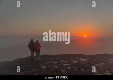 Pen y ventola, Brecon Beacons, Wales, Regno Unito. Il 10 ottobre 2018. Hill walkers godono di una drammatica sunrise dal picco del Pen y Fan, la montagna più alta nel sud della Gran Bretagna si trova in Brecon Beacons. Su ciò che è previsto per essere una calda e luminosa giornata autunnale con temperature in Galles del Sud previsto a picco su 21gradi celsius. Credito: Haydn Denman/Alamy Live News Foto Stock