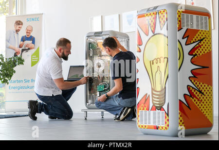 Leipzig, in Sassonia. 10 ottobre, 2018. Il 10 ottobre 2018, Germania, Lipsia: i dipendenti Mario Sattler (L) e Reiner Baeurich discutere l'installazione di un avanzamento tecnico presso un deposito di batteria di Senec GmbH. Fondata nel 2009, la società di medie dimensioni con circa 140 dipendenti sviluppa e produce batterie sistemi di storage per le case e le imprese. Con questi sistemi di storage, ad esempio i proprietari di impianti a energia solare è in grado di garantire la loro alimentazione in gran parte autonomamente e senza elettricità dalla rete. Credito: Jan Woitas/dpa-Zentralbild/dpa/Alamy Live News Foto Stock