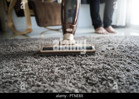 Close-up uomo utilizzando un aspirapolvere mentre la pulizia in camera Foto Stock