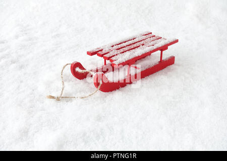 Rosso della slitta in legno con corda in coperta di neve con i fiocchi di neve. Foto Stock