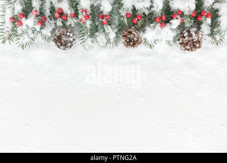 Coperte di neve sullo sfondo di Natale con naturale abete ramoscelli, pigne e bacche rosse. Vista dall'alto. Foto Stock