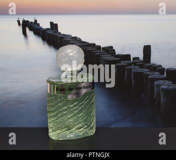 Eau de Rochas, fragranza per signore, grande bottiglia di profumo di fronte alla foto di un groyne in mare Foto Stock