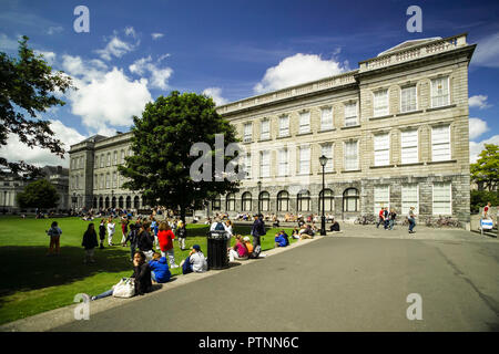 Le persone in un momento di relax a borsisti' piazza accanto alla vecchia libreria che ospita il Libro di Kells. Presso il Trinity College di Dublino. Foto Stock