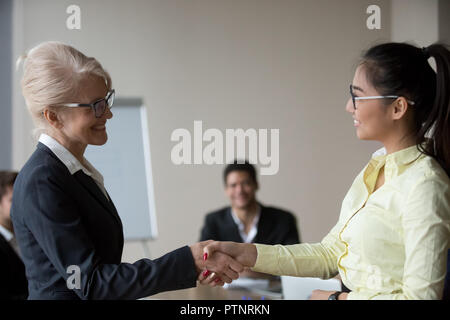 Il boss femmina handshaking dipendente asiatici congratularmi con promo Foto Stock