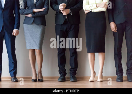 Diversi team di lavoro in piedi vicino a parete per ufficio in coda Foto Stock