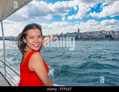 Bella donna cinese mostra popolare Torre Galata mentre fate una crociera in Istanbul, Turchia Foto Stock