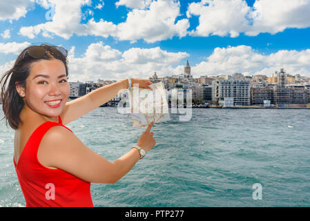 Bella donna cinese mostra Torre Galata sulla mappa mentre fate una crociera in Istanbul, Turchia Foto Stock