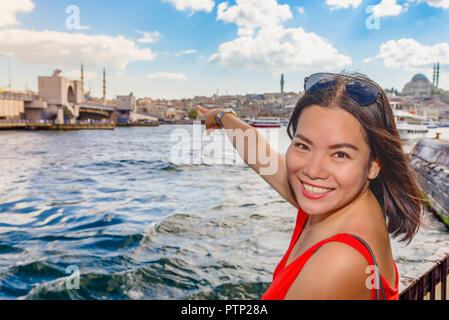 Bella donna cinese mostra il ponte Galata con la vista della Moschea Suleymaniye sullo sfondo. Foto Stock