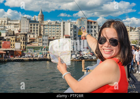 Bella donna cinese mostra Torre Galata sulla mappa oltre il Ponte di Galata a Istanbul, Turchia Foto Stock