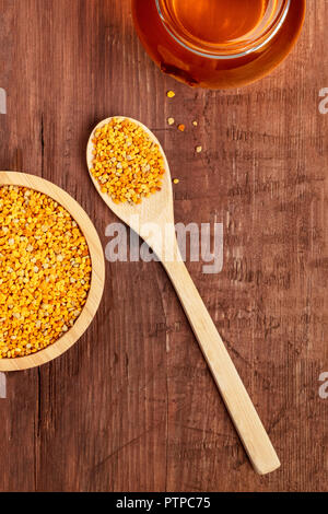 Un sano cibo biologico. Una foto aerea di polline, un vasetto di miele e un cucchiaio di legno, girato da sopra al buio su un sfondo rustico con un posto per il testo Foto Stock