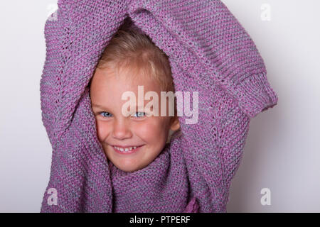 Felice bellissima bambina indossava una maglia lilla mamma del maglione e ingannare intorno a essa. concetto di infanzia, di piccole dimensioni, a crescere. Foto Stock