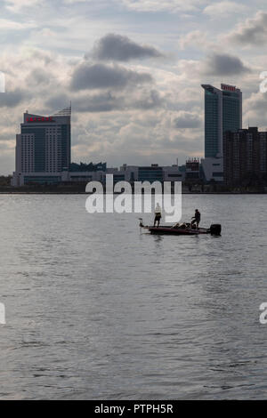 Detroit, Michigan - due uomini la pesca da una piccola barca sul Fiume Detroit. Windsor, Ontario, Canada si trova sul lato più lontano. Foto Stock