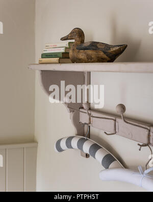 Decoy anatra e appendino con copertina rigida con libri sullo scaffale nel XVIII secolo Norfolk cottage Foto Stock