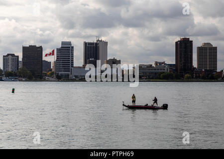 Detroit, Michigan - due uomini la pesca da una piccola barca sul Fiume Detroit. Windsor, Ontario, Canada si trova sul lato più lontano. Foto Stock