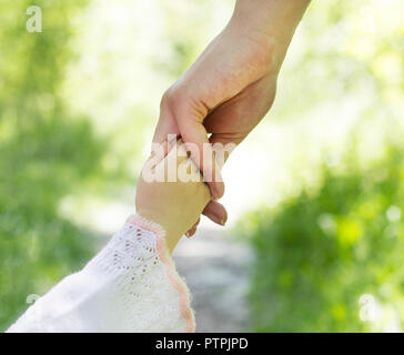 Una donna di mano trattiene un bambino piccolo la mano, close-up, natura Foto Stock