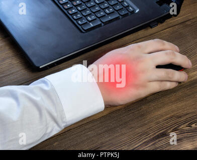 Una mano d'uomo detiene un mouse mentre si lavora al computer, un dolore nella sua mano, un close-up Foto Stock