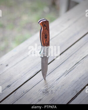 Coltello pieghevole bloccato in un tavolo di legno, close-up Foto Stock