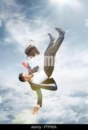 Il businessman spaventati in tuta la caduta verso il basso e urlando contro il cielo blu sullo sfondo. concetto di guasto Foto Stock