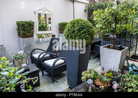 Casella ritagliata e sedie di vimini in ambiente urbano terrazza che si affaccia sul cortile interno Foto Stock