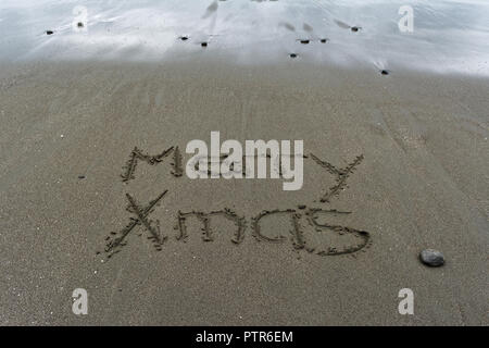 Sabbia bagnata e Merry Xmas scritto a mano nella sabbia. Foto Stock