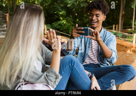 Eccitato giovane coppia multietnica di trascorrere del tempo insieme al parco, prendendo foto di ogni altro Foto Stock