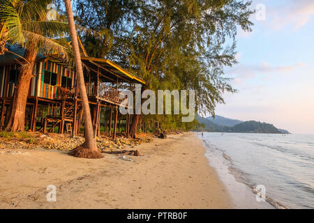 Ko Chang, Tailandia - 11 dicembre 2017. Colorate, capanna in legno su palafitte con vista al tramonto sotto alberi di casuarina sul Khlong Phrao Beach. Foto Stock