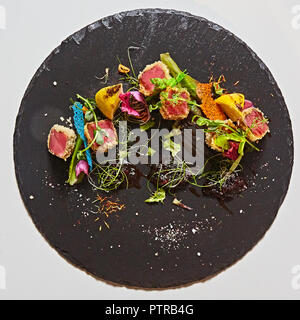 Close up di rara disseccata Ahi le fette di tonno fresco con insalata di verdure su una piastra. Foto Stock