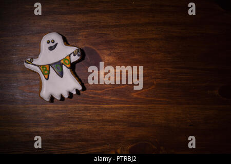 Gingerbread figura in forma di fantasmi con le bandiere che giace su di un tavolo di legno. Preparazione per la Festa di halloween Foto Stock