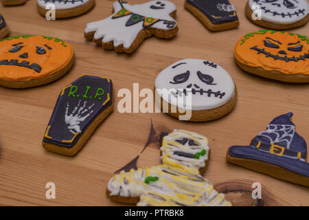 Dolce gingerbread emoticon fantasmi e zucche, streghe cappelli su una tavola di legno. Preparazione per la festa di Halloween. Dolci per la festa Foto Stock