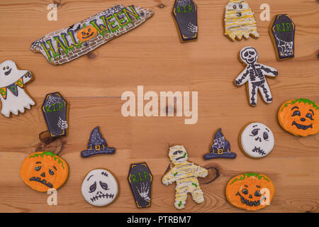 Dolce gingerbread emoticon fantasmi e zucche, streghe cappelli su una tavola di legno. Preparazione per la festa di Halloween. Dolci per la festa Foto Stock