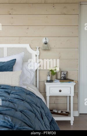 Panno blu sul letto matrimoniale con rivestimento in legno e vetro luce da parete Foto Stock