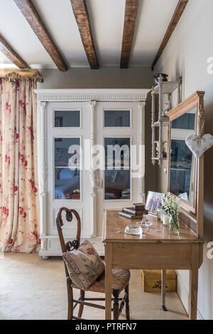 Vetro frontale armadio con tende dai motivi floreali e in legno tavolo con sedia di vimini nel XVI secolo agriturismo ristrutturazione Foto Stock