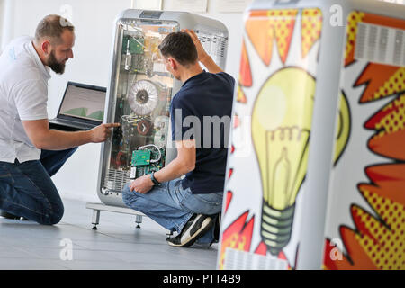 Leipzig, in Sassonia. 10 ottobre, 2018. Il 10 ottobre 2018, Germania, Lipsia: i dipendenti Mario Sattler (L) e Reiner Baeurich discutere l'installazione di un avanzamento tecnico presso un deposito di batteria di Senec GmbH. Fondata nel 2009, la società di medie dimensioni con circa 140 dipendenti sviluppa e produce batterie sistemi di storage per le case e le imprese. Con questi sistemi di storage, ad esempio i proprietari di impianti a energia solare è in grado di garantire la loro alimentazione in gran parte autonomamente e senza elettricità dalla rete. Credito: Jan Woitas/dpa-Zentralbild/dpa/Alamy Live News Foto Stock