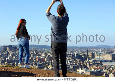 Edinburgh, Regno Unito. 10 ottobre, 2018. Visitatore prendere una fotografia del suo amico con il Castello di Edimburgo in vista sulla Arthurs Seat in una limpida giornata di sole. Credito: Craig Brown/Alamy Live News. Foto Stock