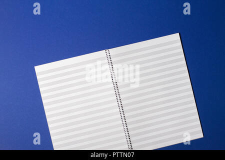 Svuotare il quaderno con pentagrams linee per le note musicali su sfondo blu Foto Stock