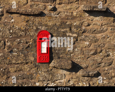 In vecchio stile anni Venti asimmetrica di piccolo rosso GR letterbox con n numero di regnal (King George - George Rex scatola a muro) nel muro di pietra in Cumbria,l'Inghilterra, Regno Unito Foto Stock