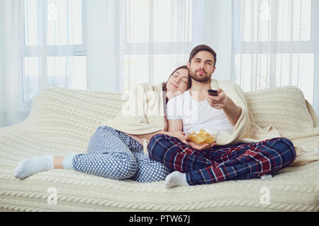 Un paio di guardare la tv comodamente seduti sul divano in camera Foto Stock