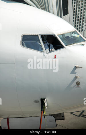 Cockpit del velivolo in piedi su una pista accanto a tunnel. Preparazione degli aeromobili in aeroporto. Foto Stock