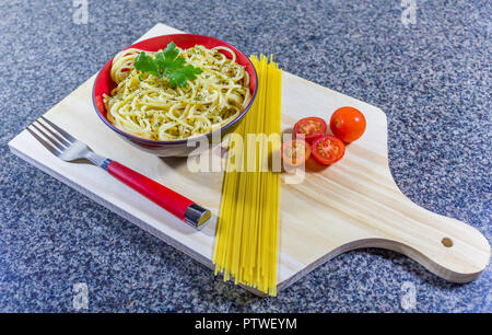 Tagliatelle con aglio e olio, servita in una ciotola con pancetta e pomodori. Foto Stock