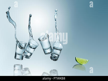 Tequila versarsi in bicchierini con uno spicchio di lime, studio shot Foto Stock