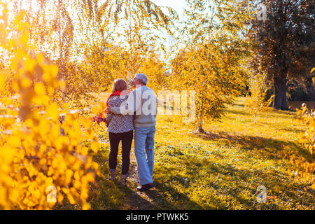 Coppia senior a piedi nella foresta di autunno. L'età media di un uomo e di una donna che abbraccia e di refrigerazione all'esterno. Persone che parlano e godersi la natura Foto Stock