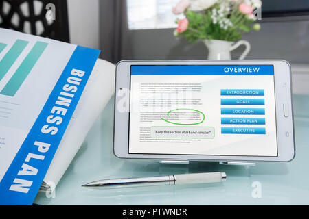 Fasi della scrittura di un business plan per soddisfare gli obiettivi aziendali, documento stampato con penna e di effettuare modifiche sul tablet PC o dispositivo mobile. Foto Stock