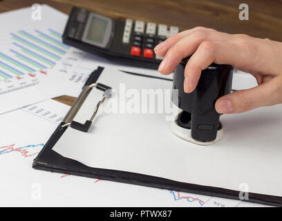 Una femmina di mano mette un sigillo su un foglio bianco Foto Stock