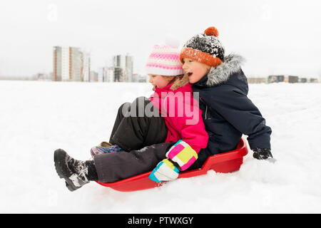 Bambini piccoli scorrevole sulla slitta giù per la collina in inverno Foto Stock