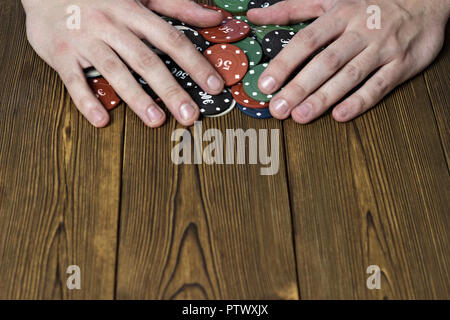 Gli uomini con le mani in mano e poker chips su uno sfondo di legno Foto Stock